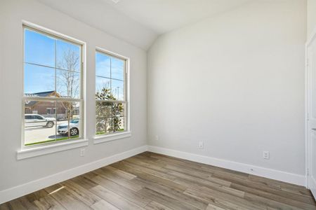 Spare room featuring hardwood / wood-style flooring, plenty of natural light, and lofted ceiling