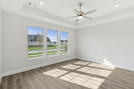 Unfurnished room featuring ceiling fan, a raised ceiling, and light hardwood / wood-style flooring