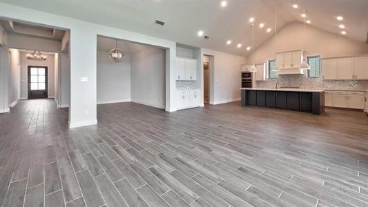 Kitchen featuring white cabinets, hardwood / wood-style flooring, decorative light fixtures, and an island with sink