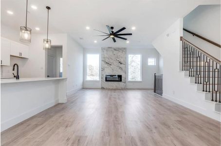 Unfurnished living room featuring ceiling fan, sink, light wood-type flooring, and a fireplace