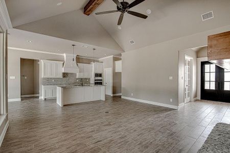 Unfurnished living room with french doors, ceiling fan, beamed ceiling, sink, and high vaulted ceiling