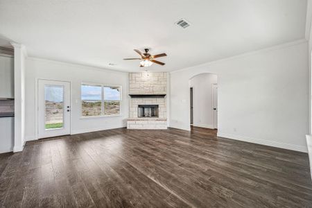 Unfurnished living room with dark wood-type flooring, crown molding, a fireplace, and ceiling fan