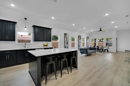 Kitchen featuring a kitchen island, light hardwood / wood-style flooring, decorative light fixtures, a breakfast bar, and tasteful backsplash
