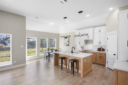 Kitchen featuring light hardwood / wood-style floors, white cabinetry, sink, a kitchen island with sink, and pendant lighting