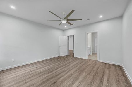 Unfurnished primary bedroom featuring light wood-type flooring, ceiling fan, and ensuite bathroom