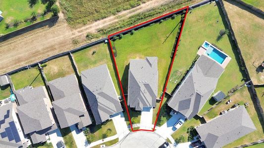 This aerial image outlines a sizable, rectangular residential lot with clear boundaries marked in red. The property is nestled within a suburban neighborhood, flanked by houses with well-maintained yards, and features open space suitable for potential landscaping or outdoor amenities.