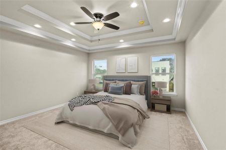 Bedroom with light carpet, multiple windows, ceiling fan, and a tray ceiling