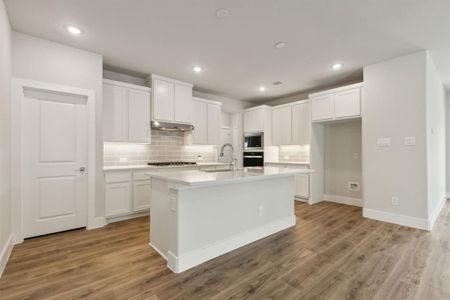 Kitchen featuring appliances with stainless steel finishes, a center island with sink, white cabinets, and light hardwood / wood-style floors