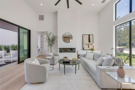 Living room featuring ceiling fan, light hardwood / wood-style flooring, and a high ceiling