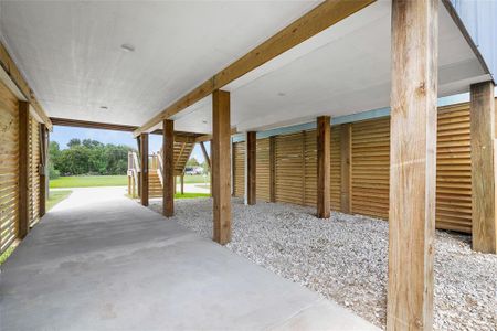 This is the rear view of the covered carport area, offering ample space for parking and outdoor activities, complemented by a louvered wood siding for added privacy and aesthetic appeal.