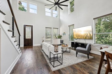 Living room featuring a high ceiling, dark wood-type flooring, and ceiling fan