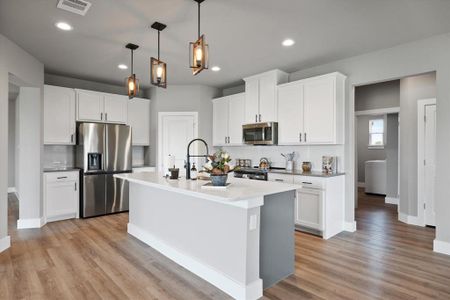 Kitchen featuring white cabinetry, an island with sink, pendant lighting, stainless steel appliances, and light wood-type flooring