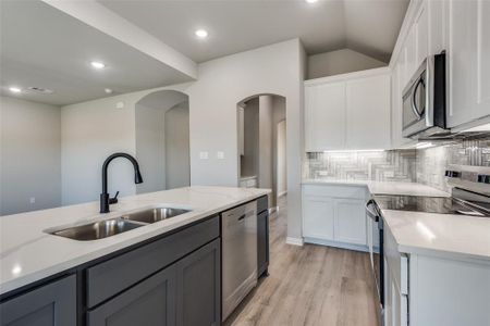 Kitchen with white cabinetry, decorative backsplash, appliances with stainless steel finishes, and sink