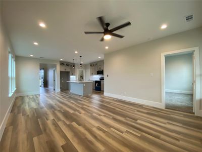 Unfurnished living room with ceiling fan, sink, and hardwood / wood-style floors