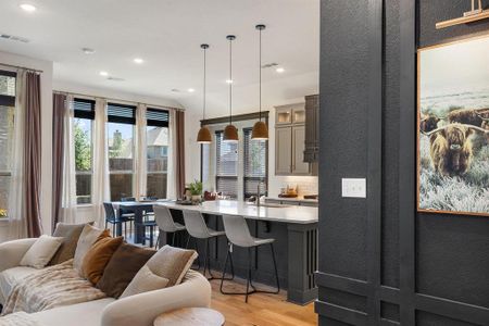 Kitchen with decorative light fixtures, tasteful backsplash, a kitchen bar, sink, and light wood-type flooring