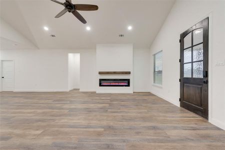 Unfurnished living room with light hardwood / wood-style floors, vaulted ceiling, and ceiling fan