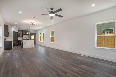 Unfurnished living room featuring sink, ceiling fan, and dark hardwood / wood-style flooring