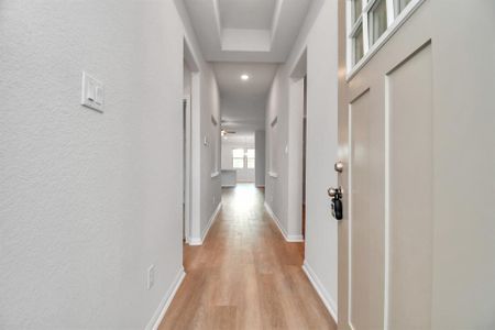 Step into this bright and welcoming entryway with light hardwood floors, tray ceiling, and recessed lighting, offering a modern and spacious feel as you step inside.