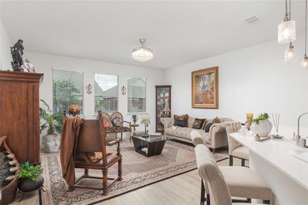 Living room featuring light wood-style LVP flooring and a notable chandelier