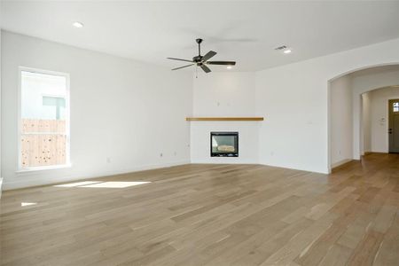 Unfurnished living room featuring ceiling fan and light hardwood / wood-style flooring