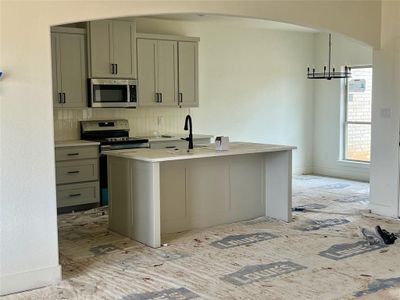 Kitchen featuring tasteful backsplash, a center island with sink, pendant lighting, sink, and a chandelier