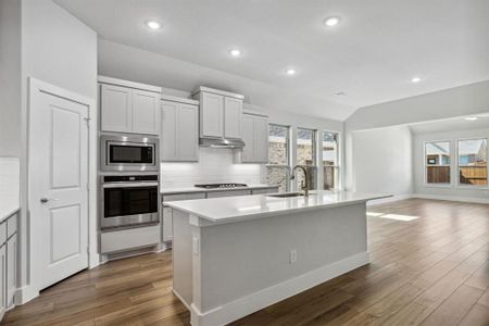 Kitchen with a wealth of natural light, appliances with stainless steel finishes, sink, and an island with sink