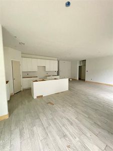 Kitchen with white cabinetry, a center island, and light wood-type flooring