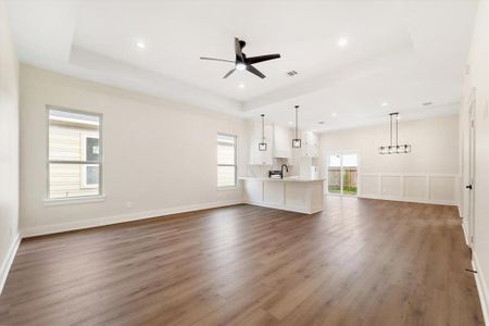 The generously sized living area is enhanced with recessed lighting, a contemporary ceiling fan, and a refined tray ceiling. It flows seamlessly into the adjacent kitchen and dining areas, offering an ideal open-concept layout.