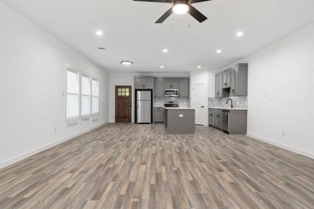 Kitchen featuring gray cabinets, stainless steel appliances, wood-type flooring, and a kitchen island