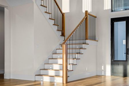 Staircase with a towering ceiling and hardwood / wood-style floors