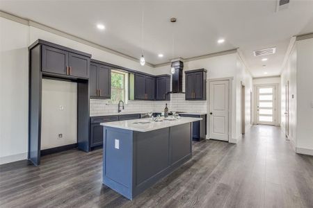 Kitchen featuring a wealth of natural light, a kitchen island, wall chimney exhaust hood, and crown molding