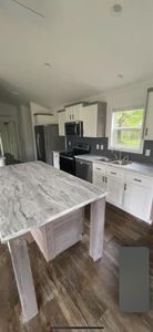 Kitchen featuring dark hardwood / wood-style flooring, appliances with stainless steel finishes, a center island, sink, and white cabinetry