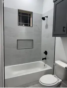 Bathroom with toilet and tiled shower / bath