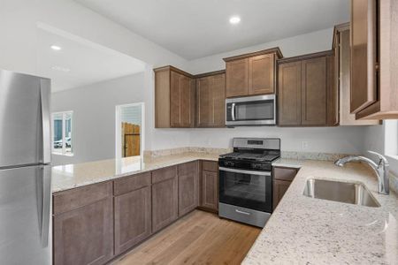 Kitchen with appliances with stainless steel finishes, light stone countertops, and sink