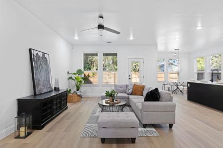 Living room with ceiling fan, a healthy amount of sunlight, sink, and light wood-type flooring