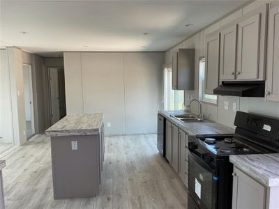 Kitchen featuring light hardwood / wood-style flooring, gray cabinetry, black range, and a kitchen island