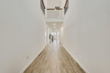 Corridor featuring light hardwood / wood-style flooring and a towering ceiling