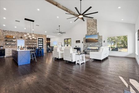 Living room with brick wall, high vaulted ceiling, ceiling fan, and dark wood-type flooring