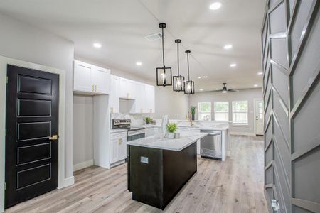 Kitchen with decorative light fixtures, ceiling fan, a center island, light wood-type flooring, and appliances with stainless steel finishes