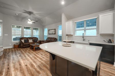 Kitchen featuring ceiling fan, white cabinets, sink, a kitchen island, and vaulted ceiling