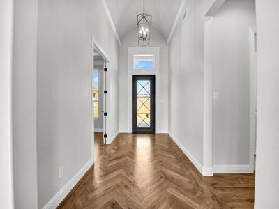 Entrance foyer with parquet flooring, a notable chandelier, and vaulted ceiling