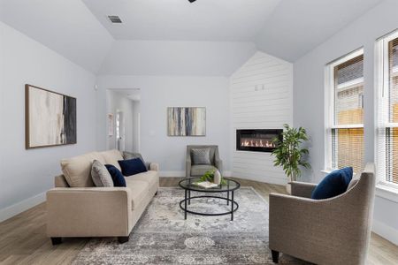 Living room with light hardwood / wood-style flooring, lofted ceiling, and a large fireplace