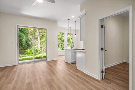 Open concept floor plan is bright and airy. The living room features a sliding glass door to the back porch. The home office and kitchen are beyond.