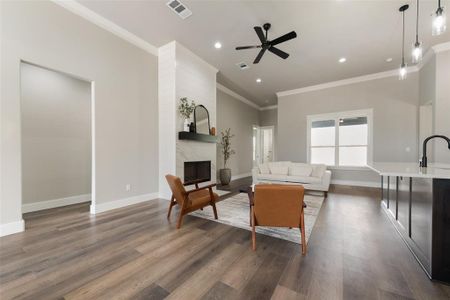 Living room with dark hardwood / wood-style floors, a fireplace, ornamental molding, sink, and ceiling fan