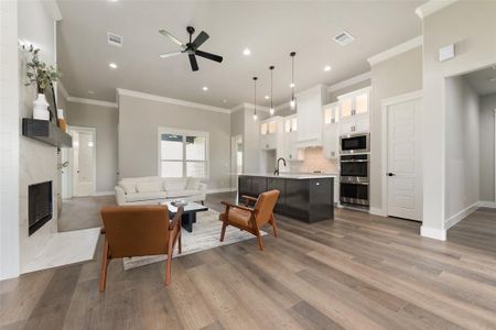 Living room with hardwood / wood-style floors, ceiling fan, ornamental molding, and a premium fireplace