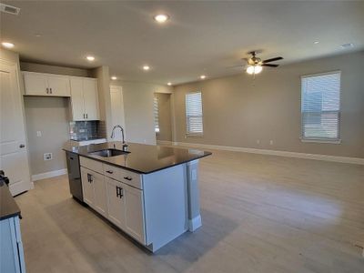 Kitchen featuring ceiling fan, an island with sink, white cabinetry, and sink