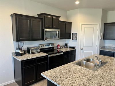 Kitchen featuring light stone countertops, appliances with stainless steel finishes, and sink