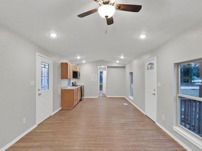 Kitchen with light wood-type flooring, stainless steel range with electric stovetop, ceiling fan, and vaulted ceiling