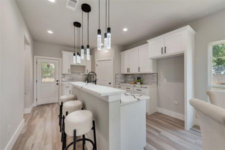 Kitchen with light hardwood / wood-style floors, decorative light fixtures, a wealth of natural light, and backsplash