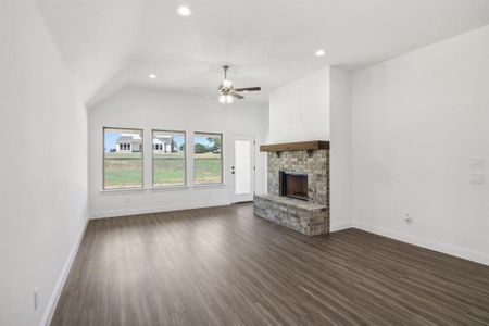 Unfurnished living room with ceiling fan, a fireplace, dark hardwood / wood-style floors, and vaulted ceiling